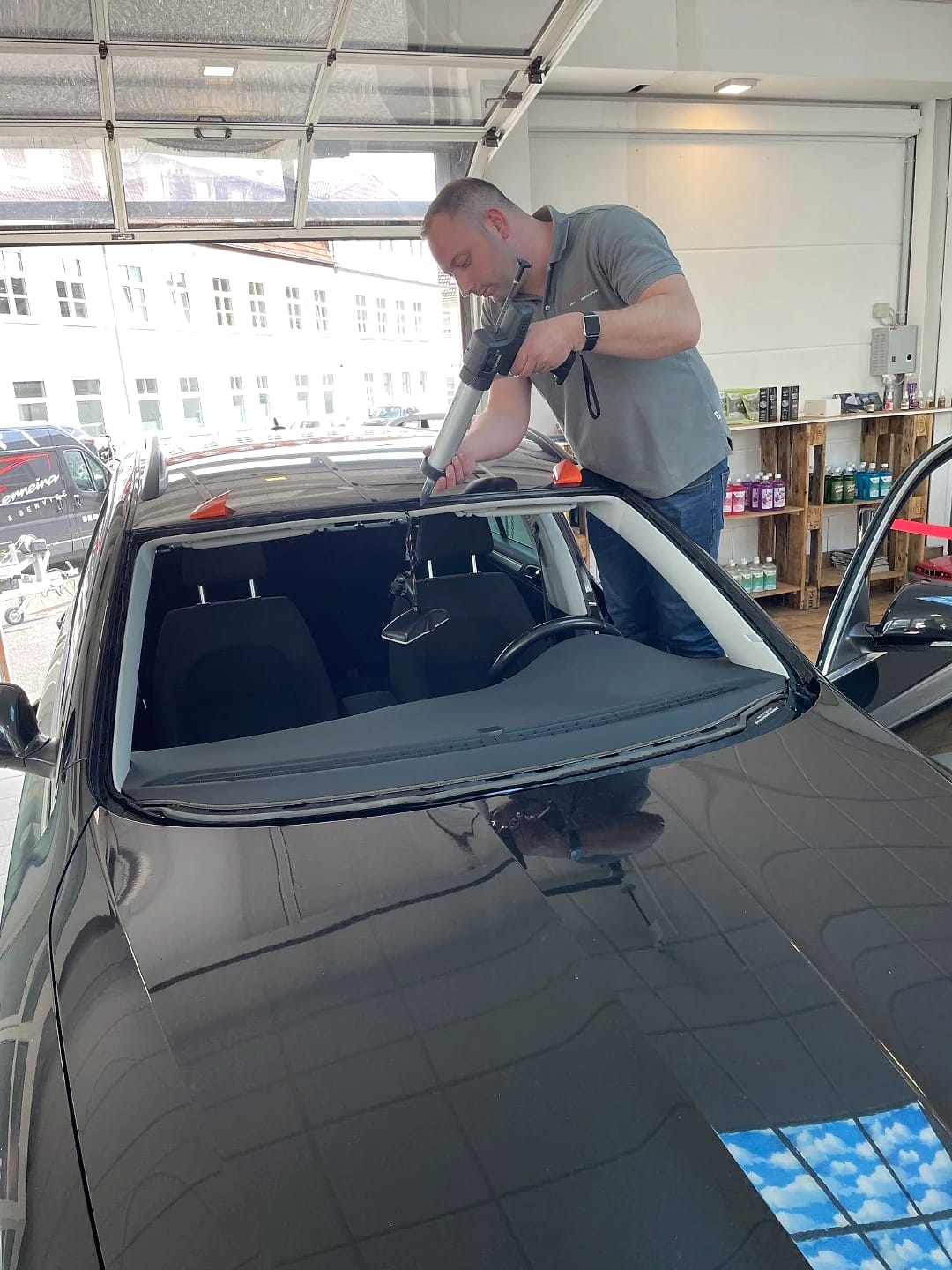 Mitarbeiter von Car Ferreira setzt in der Werkstatt in Iserlohn eine neue Frontscheibe in einen schwarzen Kombi ein